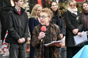 STW Society Chair, Mau Ellmann, holding a red mic and giving a speech at the statue inauguration